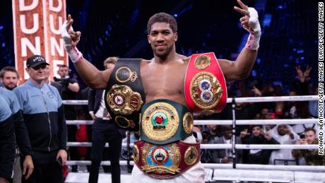 Joshua poses for a photo with the IBF, WBA, WBO &amp; IBO World heavyweight title belts after beating Andy Ruiz Jr.