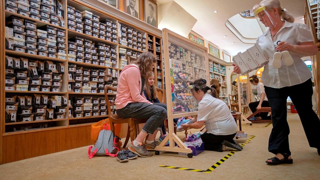 Sue Stamp fits a young girl with a new pair of shoes after W.J. French and Son reopened in Southampton, England, on June 15.