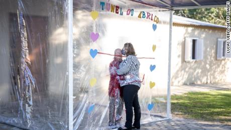 A daughter and mother embrace through the thick plastic curtain and sleeves of the &quot;hug tunnel.&quot;