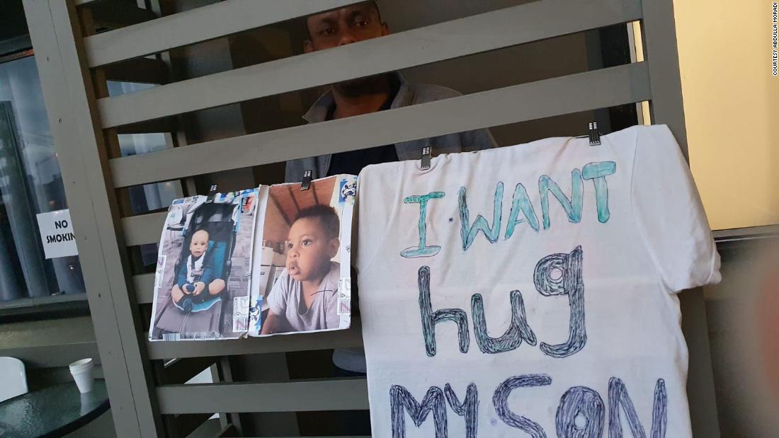 Saif Ali Saif peers out from his hotel room balcony where he has hung images of his three-year-old son.