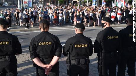 Riot police officers watch opposition supporters in Minsk on June 19.