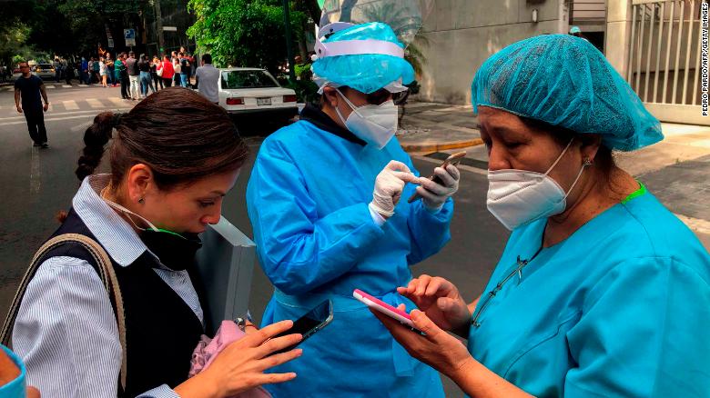 Health workers use their mobile phones on a street during a quake in Mexico City, on June 23.