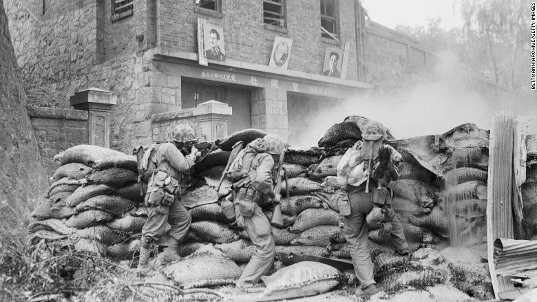 US Marines take cover behind a barricade as street fighting rages in Pyongyang. On the wall in the background are images of Soviet leader Joseph Stalin and North Korean leader Kim Il Sung.