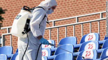 A sanitary worker in protective gear sprays disinfectant on seats in Red Square before the parade.