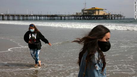 A mother and daughter wear masks as they visit the beach Tuesday in Santa Monica, Calif. 