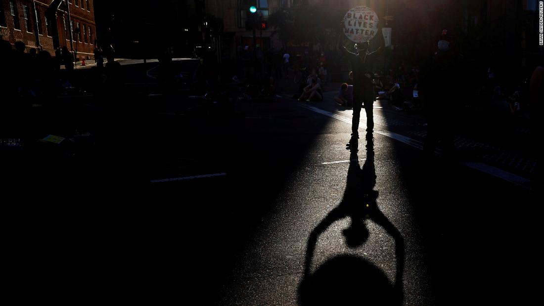 A man holds a Black Lives Matter sign as demonstrators block a Boston intersection on June 23. 