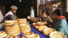Un bărbat din Uighur vinde tradițional pâine plată cumpărătorilor de sex feminin de-a lungul străzii Xinjiang din Beijing în 1999.