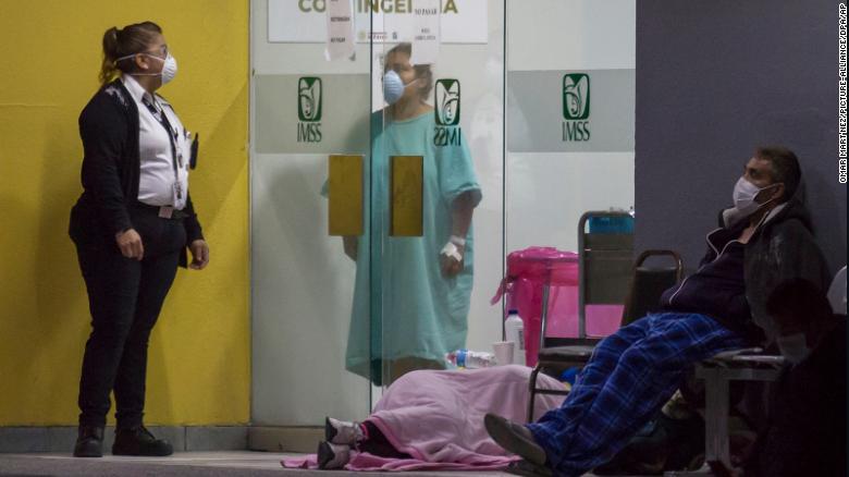 People wearing face masks wait outside an emergency room in Tijuana to be tested for coronavirus in April. 