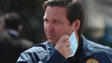 Florida Gov. Ron DeSantis takes his mask off as he prepares to speak during a press conference at the Hard Rock Stadium testing site on May 06, 2020 in Miami Gardens, Florida.