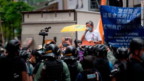 El ex legislador y activista de toda la vida Lee Cheuk-Yan habla a una multitud en Causeway Bay mientras la policía antidisturbios está en el fondo. Fue arrestado poco después.