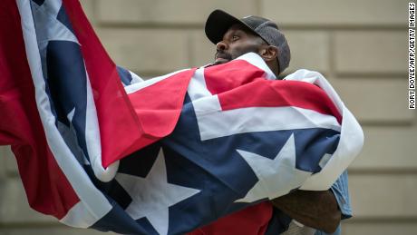 A staff member raises the state flag for the flag retirement ceremony at the Mississippi State Capitol building in Jackson, Mississippi on July 1, 2020. (Photo by Rory Doyle / AFP)