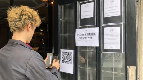 Un bebedor escanea un código QR para ingresar información de contacto antes de ingresar a un pub en el sur de Londres.