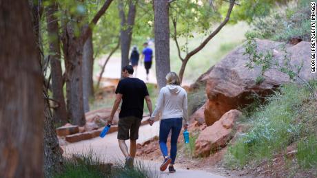 Hikers walking along a paved trail in Utah&#39;s Zion National Park, Utah, which had been closed due to the pandemic.