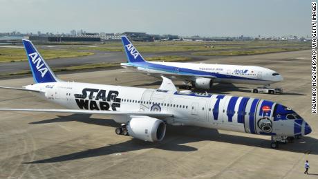 An All Nippon Airways (ANA) Boeing 787-9 aircraft in the livery of Star Wars droid character R2-D2 (front) is seen on the tarmac at Tokyo&#39;s Haneda airport on October 14, 2015, as part of the company&#39;s Star Wars project. The Boeing aircraft is scheduled to go into service on international routes after a fan appreciation flight event on October 17. / AFP / KAZUHIRO NOGI        (Photo credit should read KAZUHIRO NOGI/AFP via Getty Images)