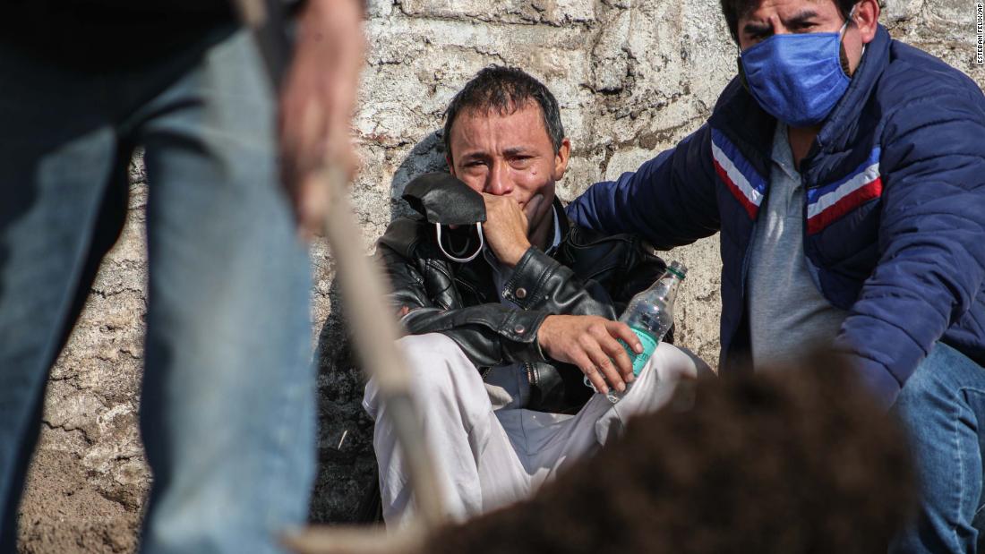 Peruvian migrant Jose Collantes cries as he watches cemetery workers bury his wife, Silvia Cano, in Santiago, Chile, on July 3. She died of coronavirus complications, according to Collantes.