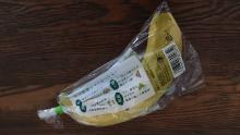 O singură banană este înfășurată într-o folie de plastic strânsă.