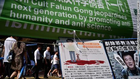 Los peatones pasan pancartas que critican el movimiento espiritual de Falun Gong que se exhibió en una acera en Causeway Bay, una popular zona comercial en Hong Kong, el 25 de abril de 2019.