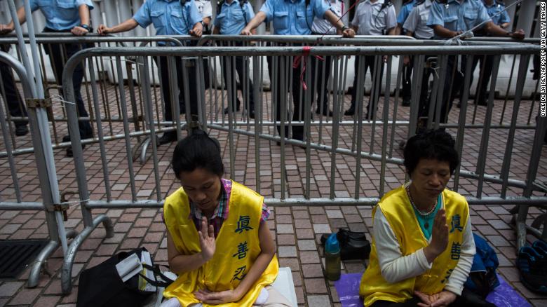 Falun Gong members meditate as policemen watch demonstrators during a pro-democracy protest in Hong Kong on May 18, 2016.