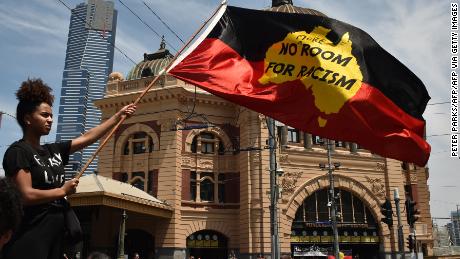 A woman waves the Aboriginal flag on January 26, 2018, during a rally to mark what many Indigeous Australians call &quot;Invasion Day.&quot;