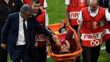 Cristiano Ronaldo este mângâiat de antrenorul Portugaliei, Fernando Santos, în timp ce este transportat pe o targă în afara terenului în finala Euro 2016.