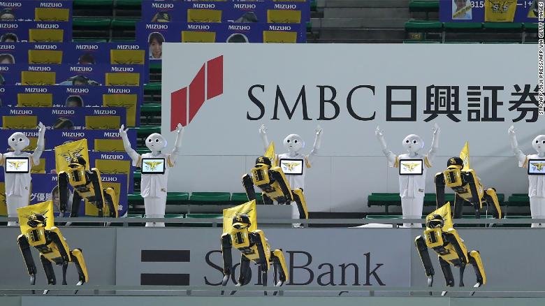 SoftBank Corp's humanoid robots Pepper (white) and Boston Dynamics' robots SPOT (yellow) dance and sing before the Nippon Professional Baseball league match between SoftBank Hawks and Rakuten Golden Eagles in Fukuoka on July 10, 2020. 