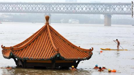 Sakinleri, 8 Temmuz'da Çin'in Hubei eyaletindeki Wuhan'daki su dolu Yangtze Nehri'nin battığı nehir kenarındaki bir köşkten yüzüyorlar.