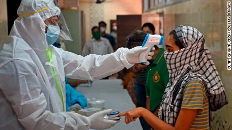 A medical volunteer takes temperature reading of a woman in Mumbai on July 10, 2020.