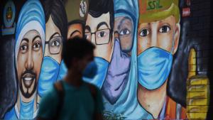 A youth walks past a mural of frontline workers after the government eased a nationwide lockdown imposed as a preventive measure against the COVID-19 coronavirus in New Delhi on July 14, 2020. (Photo by Sajjad HUSSAIN / AFP) (Photo by SAJJAD HUSSAIN/AFP via Getty Images)