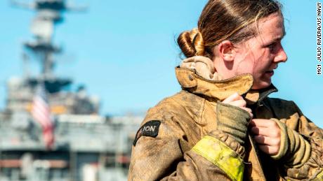 A sailor takes off her firefighting ensemble after combating a fire aboard the amphibious assault ship USS Bonhomme Richard.