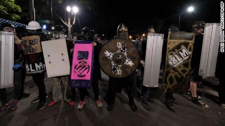 Parts of this image have been blurred by CNN to obstruct profanity. Protesters holding shields line up in the street opposite the Edith Green Wendell Wyatt federal building in Portland early Saturday.