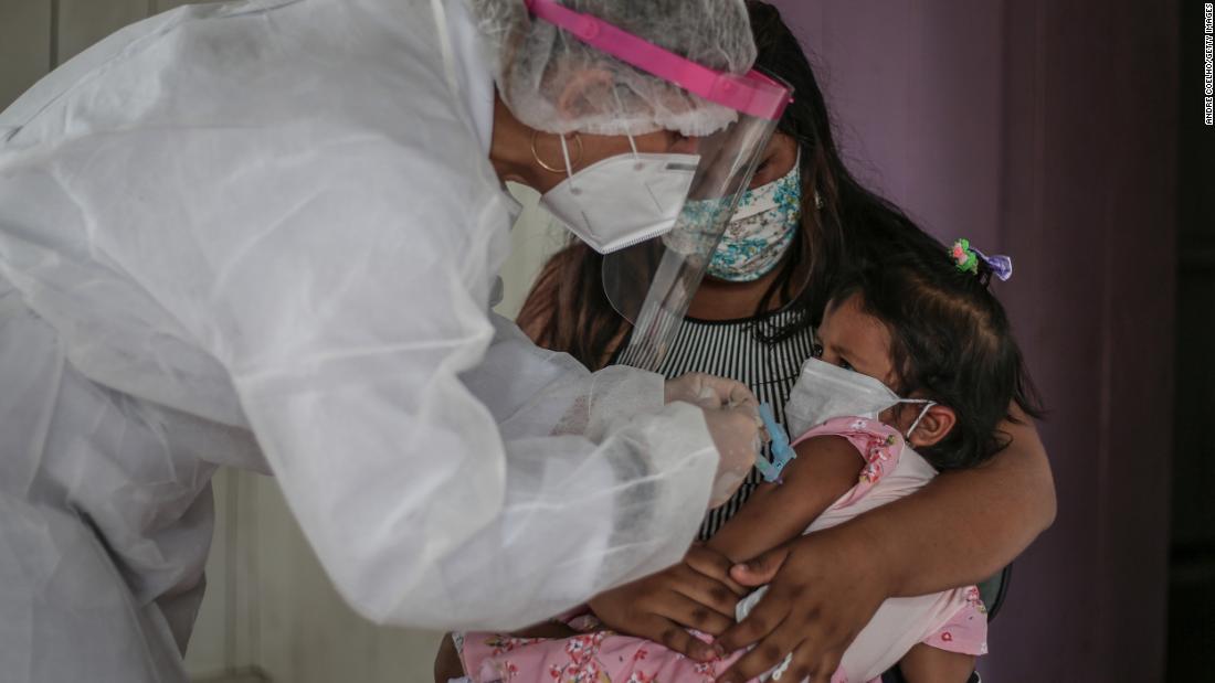 &lt;strong&gt;Brazil:&lt;/strong&gt; A mother holds her daughter while a nurse wearing a protective mask and shield gives the child a flu vaccine. 