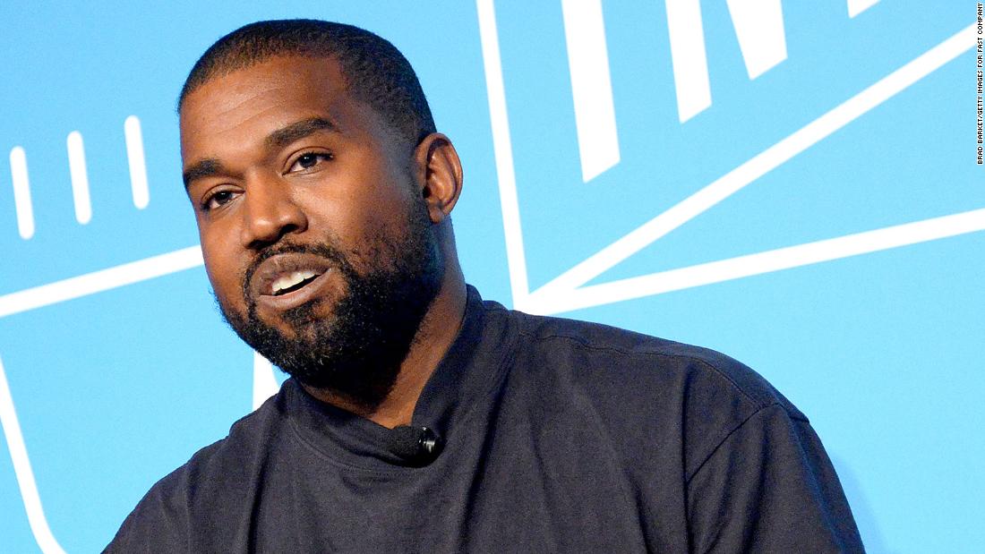 Kanye west smiling, dressed in the us president's suit in front of the  white house