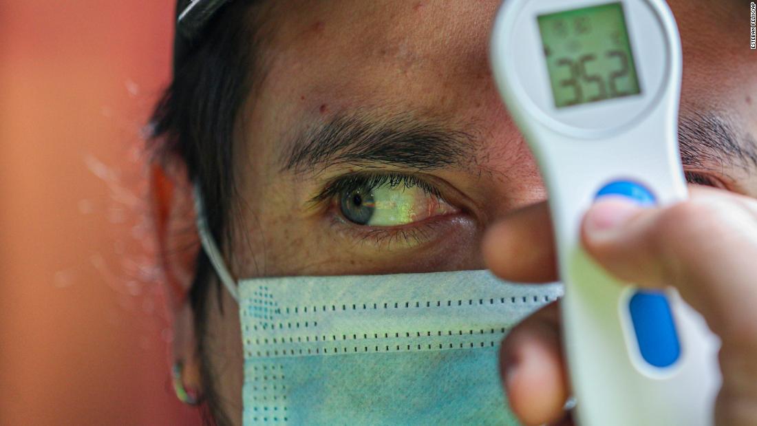 A worker measures a man&#39;s temperature before allowing him to enter La Vega market in Santiago, Chile, on July 19.