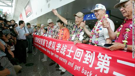US World War II veterans, including former Flying Tigers, pose for pictures with a banner as a cheering crowd welcome them at the Chongqing Jiangbei Airport on August 18, 2005.