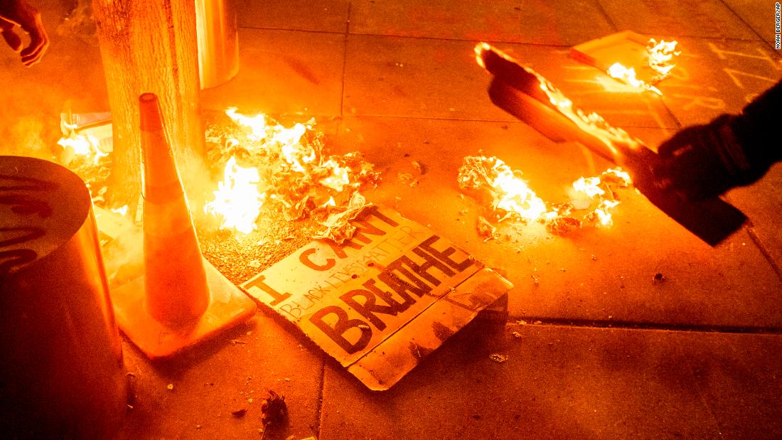 A Black Lives Matter protester burns a sign outside the courthouse early on July 21.