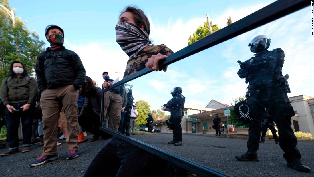 A man holds a mirror in front of police guarding the Multnomah County Sheriff&#39;s Office on May 30.