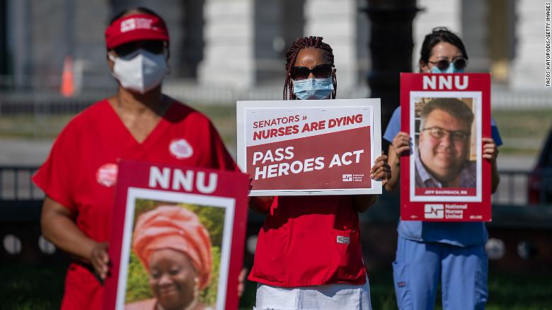 Nurses hold signs of nurses who&#39;ve died from coronavirus at a public vigil in front of the US Capitol. 