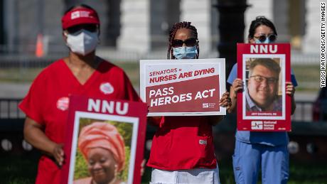 Nurses hold signs of nurses who&#39;ve died from coronavirus at a public vigil in front of the US Capitol. 
