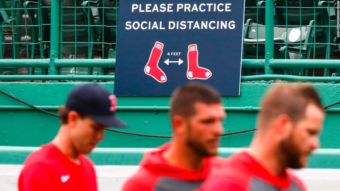 Boston players walk by a sign encouraging social distancing at Fenway Park.