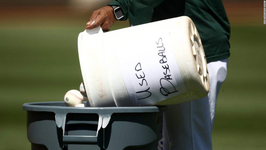 A coach dumps a bucket of used baseballs during workouts in Oakland on July 5. During the season, balls will be taken out of play after they&#39;ve been handled by multiple players. Then the balls will be sanitized and recycled days later.