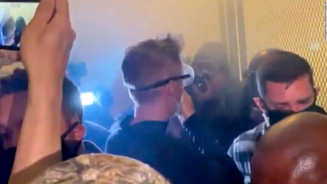 In this image made from video and released by Jonathan Maus, Portland Mayor Ted Wheeler, center, stands near a courthouse fence as &lt;a href=&quot;https://www.cnn.com/2020/07/23/us/portland-protests-mayor/index.html&quot; target=&quot;_blank&quot;&gt;tear gas engulfs the area&lt;/a&gt; on July 23. Wheeler had joined crowds to listen to protesters and answer their questions in response to violent clashes between demonstrators and federal forces.