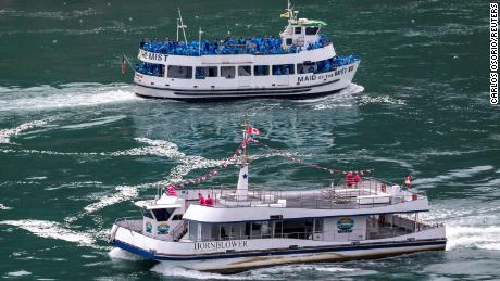 A people-laden tour boat operated by US company Maid of the Mist sails past a sparsely populated boat run by Canada&#39;s Hornblower Niagara Cruises.