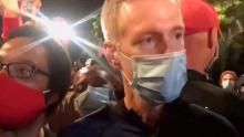 In this image made from video released by Karina Brown, Portland Mayor Ted Wheeler, right, stands at a fence guarding a federal courthouse as tear gas drifts by early July 23, 2020, in Portland Oregon, during another night of protest against the presence of federal agents sent by President Donald Trump to quell unrest in the city. (Karina Brown via AP)