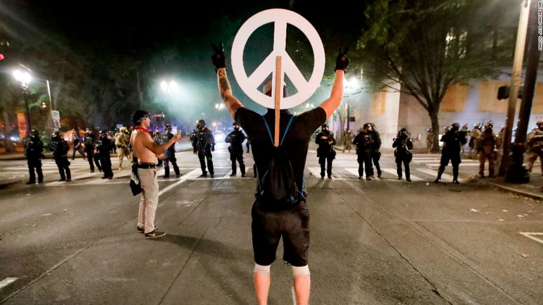 A demonstrator flashes peace signs at federal officers on July 29.