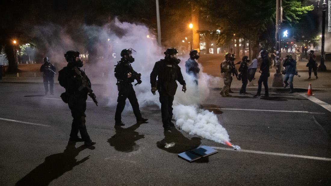 Police and federal officers walk through the street on July 28, deploying tear gas and other methods to disperse protesters.