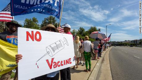 A protester holds an anti-vaccination sign as supporters of President Donald Trump rally to reopen California as the coronavirus pandemic continues to worsen, on May 16, 2020, in Woodland Hills, California. Coronavirus conspiracy theories fuel anti-vaccination protests.