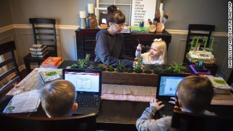 Austinville Elementary third grade teacher Emily Williams helps her daughter Lily, 3, as her two sons Braden, 10, bottom left, and Landen, 8, complete virtual school assignments in June at their home in Decatur, Alabama.