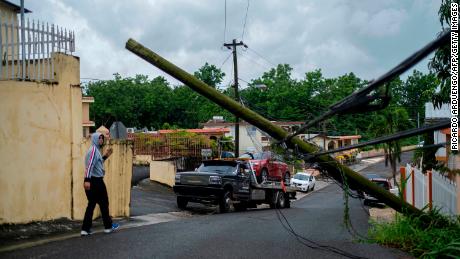 A man guides a tow truck under a downed power line pole after Tropical Storm Isaias affected the area in Mayaguez, Puerto Rico, on Thursday.