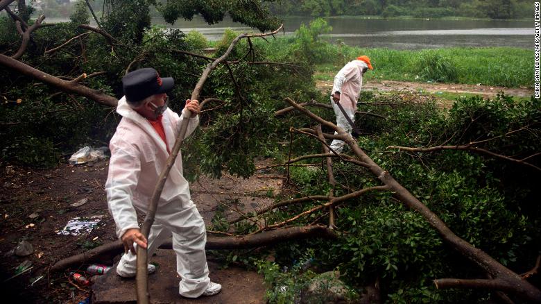 Fire and rescue workers cut the branches of a tree that fell under  heavy rain caused by Isaias in Santo Domingo, Dominican Republic, on Thursday.