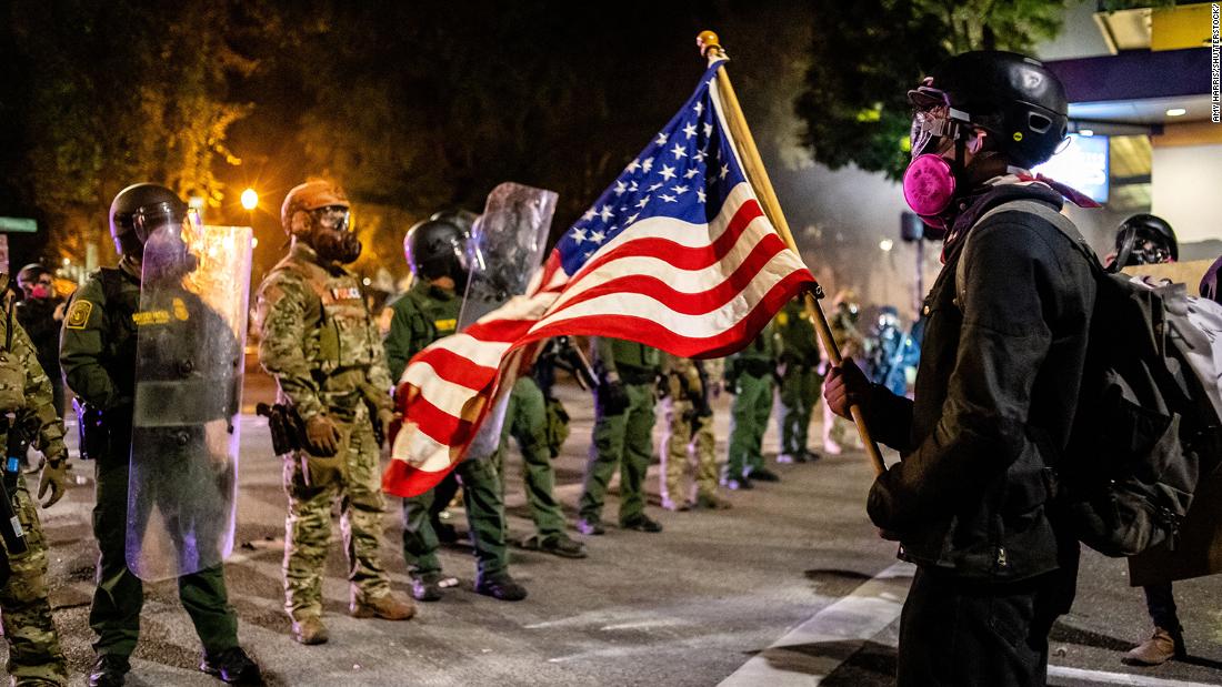 A protester holds up an American flag in front of federal officers on July 30.